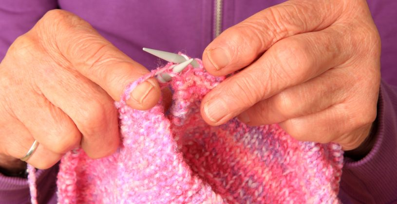 Senior woman’s hands knitting a soft, pink blanket. Knitting can help maintain fine motor skills, muscle memory and coordination