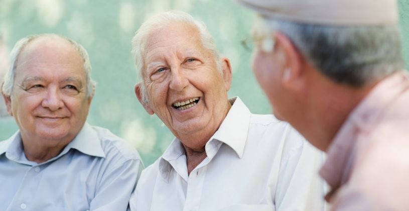 A group of senior men chat and laugh. Friendships are important at any age, but can be especially helpful for staving off feelings of loneliness for those 65 and older.