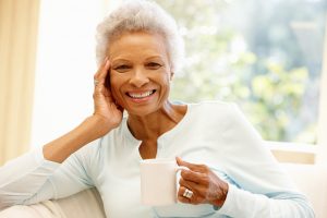 Happy senior woman holding a cup of tea. During a pandemic the necessity of continuing a daily self-care routine can't be overstated.