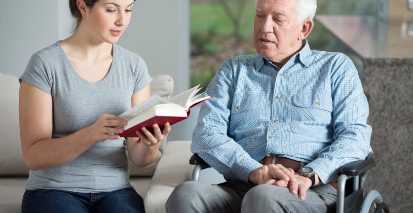 Caregiver reading to a senior with aphasia. Aphasia is a disorder that robs the afflicted of the ability to understand language and communicate normally.