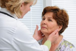 Doctor examines a senior woman's thyroid glands. Thyroid disease impacts around 20 million people in the U.S.