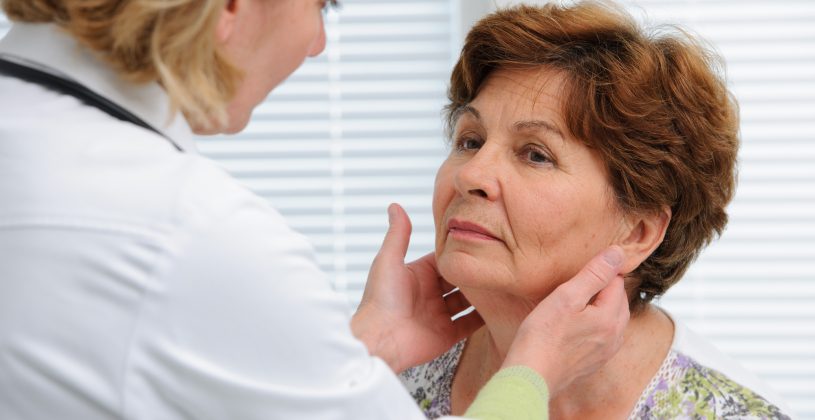 Doctor examines a senior woman's thyroid glands. Thyroid disease impacts around 20 million people in the U.S.