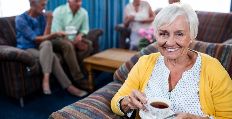 Residents of an assisted living community drinking coffee and socializing in a lounge.