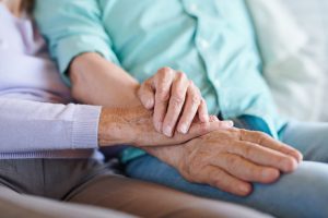 Image of senior couple holding hands to symbolize spousal caregiving.