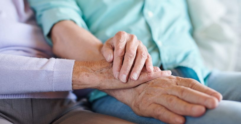 Image of senior couple holding hands to symbolize spousal caregiving.