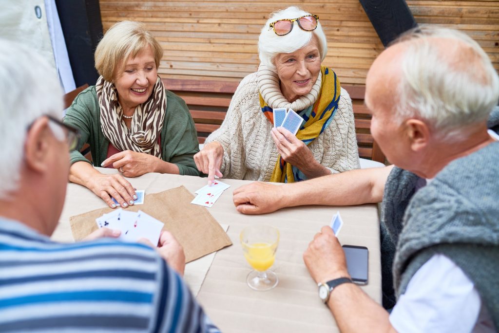 four seniors sitting around a table playing a card game together